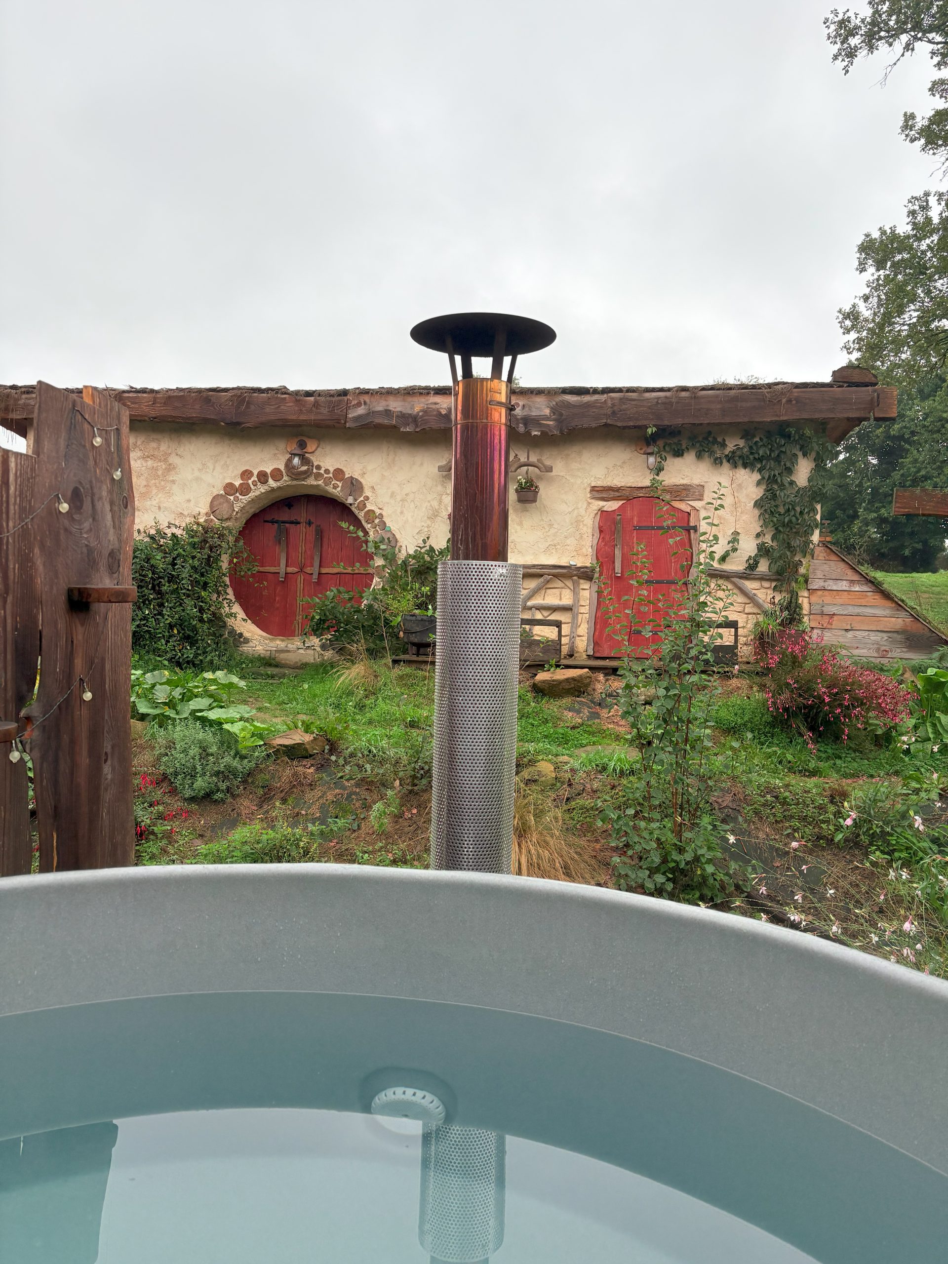 Porte ronde en bois sculpté de la Maison Sacquet - Entrée hobbit avec tonneaux décoratifs